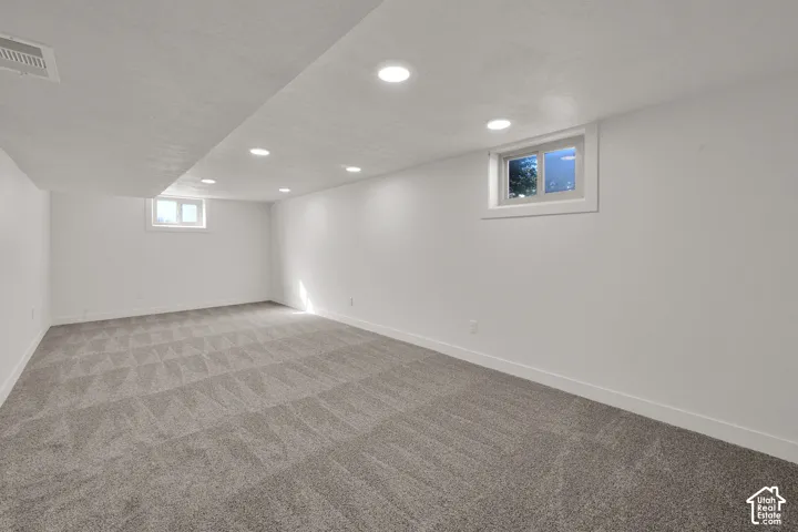 Spacious room featuring new carpeting, recessed lighting, white walls, and multiple windows