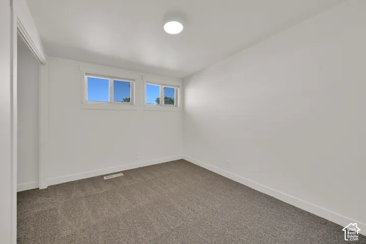 White interior walls, two transom windows, recessed ceiling light, and gray carpeting