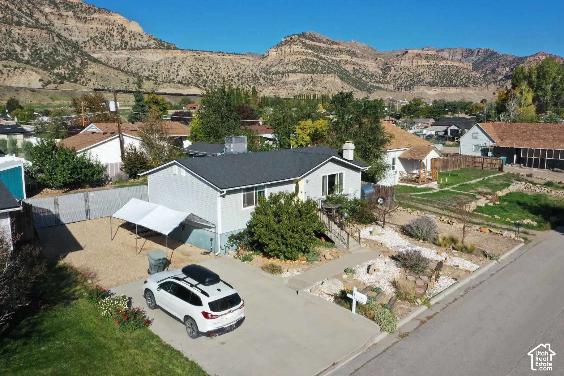 Single-story residence featuring light-colored siding, a dark-toned roof, and a front yard with xeriscaping