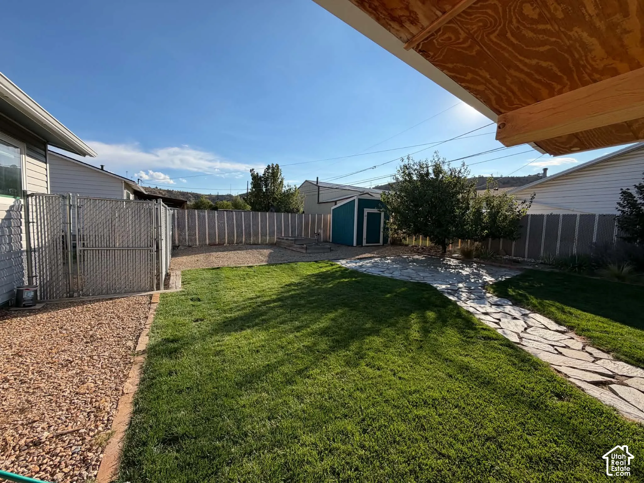 Expansive backyard featuring a manicured lawn, flagstone pathway, gravel landscaping, and privacy fencing