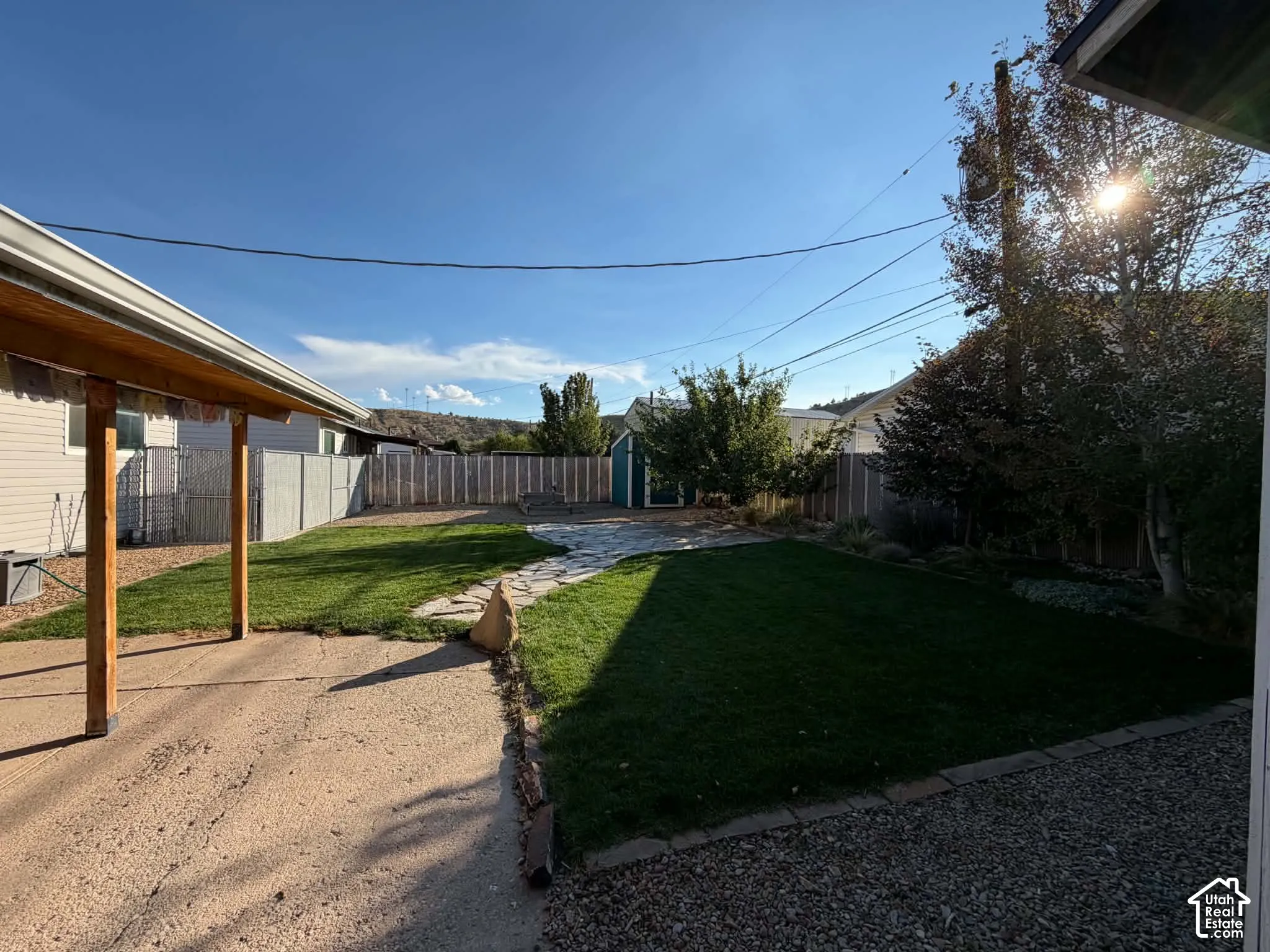 Spacious backyard featuring a manicured lawn, flagstone pathway, and perimeter fencing