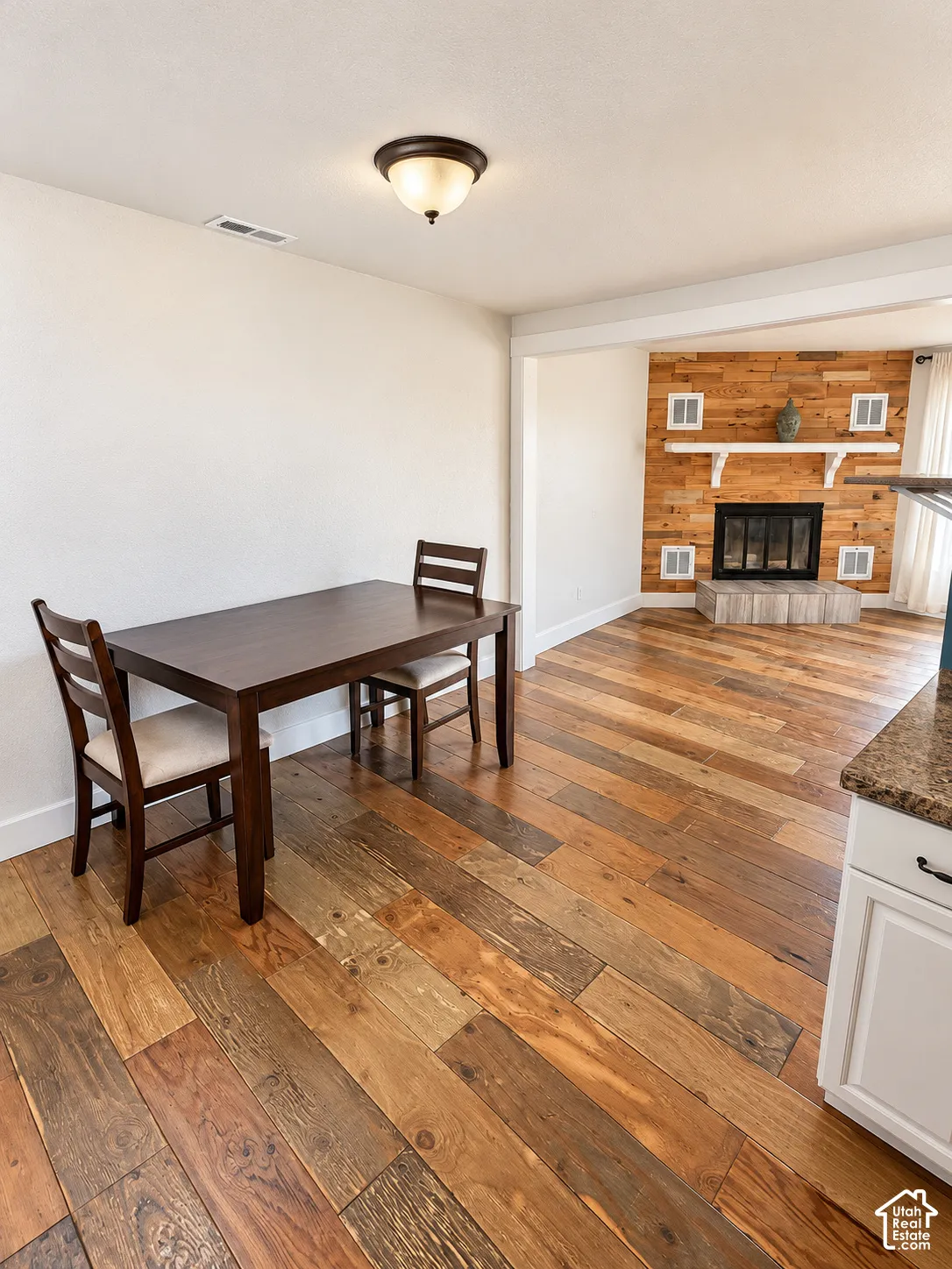 Wood-finish flooring throughout, featuring a recessed fireplace with a natural wood-finish accent wall