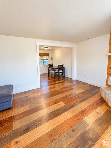Wood-finish flooring throughout, white wall finishes, and a fireplace with a wood-finish hearth