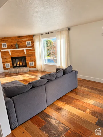 Wood-finish flooring throughout, featuring a fireplace with a wood-paneled surround and built-in mantle