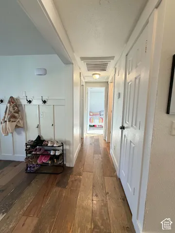 Wood-finish flooring extending through a hallway with white paneled walls and multiple doors