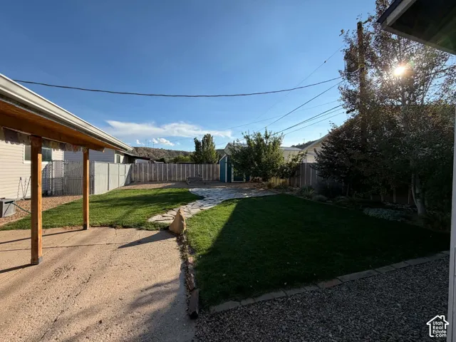 Spacious backyard featuring a manicured lawn, flagstone pathway, and perimeter fencing