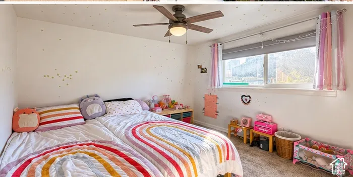 White walls with star-patterned accents, a ceiling fan with integrated lighting, and a large window with a roller shade