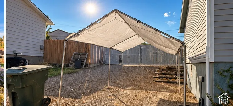 Spacious covered patio with sturdy metal frame and tan canopy, offering sheltered outdoor space