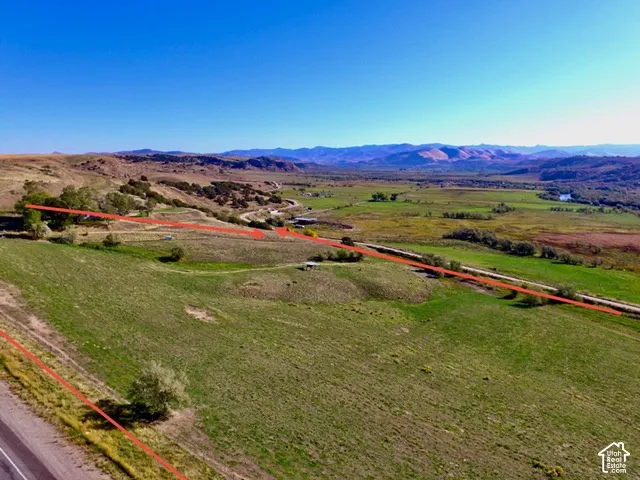 Expansive property featuring verdant grasslands, mature trees, and mountainous terrain