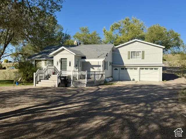 Light-colored siding exterior with a multi-level deck, multi-pane front door, and an attached two-car garage