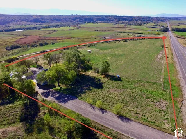 Expansive land parcel with surrounding agricultural fields, mature trees, and direct highway frontage