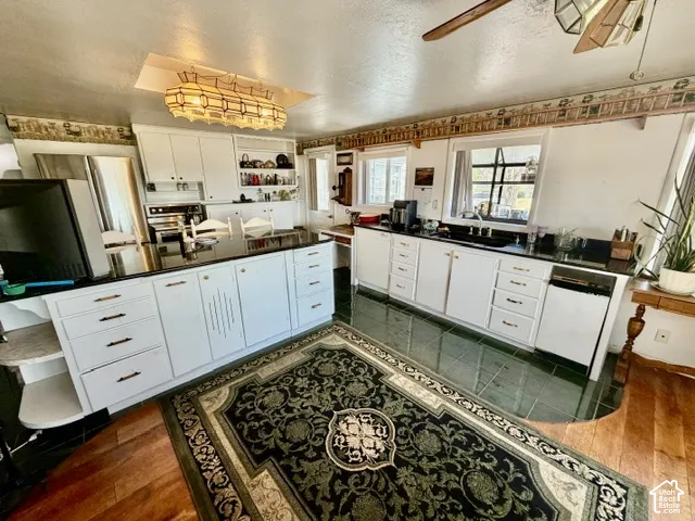 Spacious kitchen featuring white cabinetry with ample storage, stainless steel appliances, dark countertops, and dual islands providing generous workspace