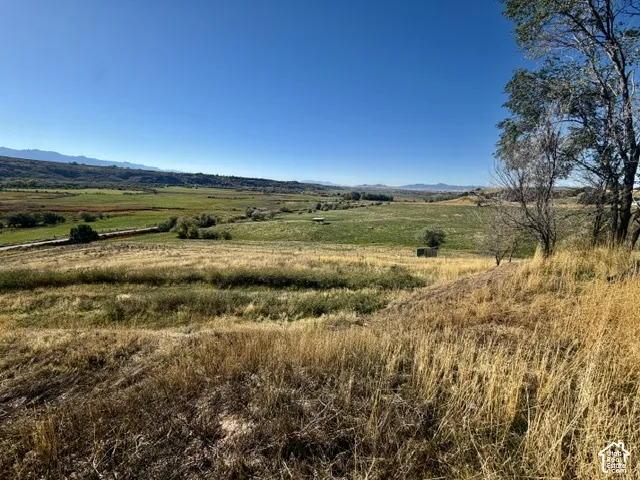Expansive landscape featuring distant mountains, verdant fields, and a clear sky