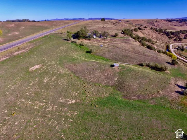 Expansive rural landscape featuring rolling hills, a paved road, and a small structure