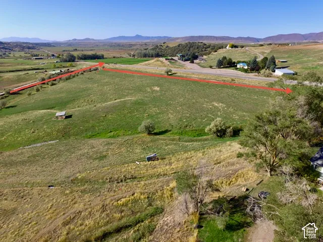 Expansive parcel featuring green fields, distant mountains, and established trees