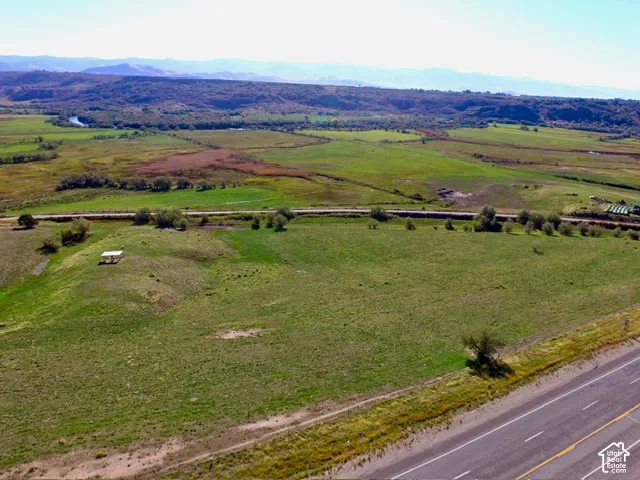 Expansive green landscape with distant mountains, a river, and a highway
