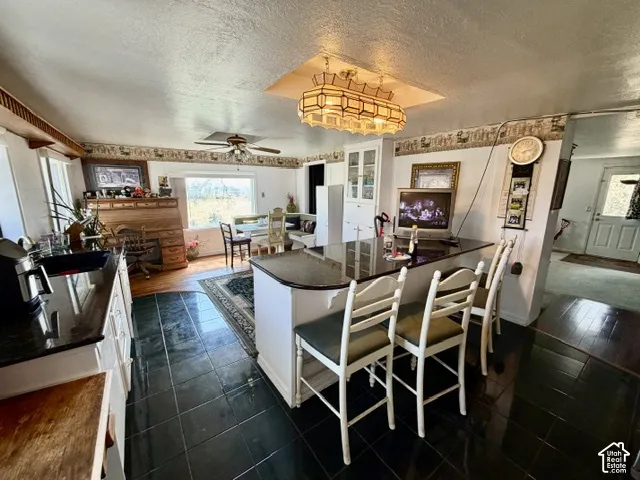 Kitchen featuring a peninsula island, built-in cabinetry with glass panel doors, and black tile flooring