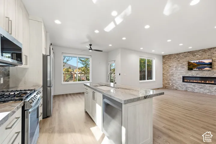 Kitchen featuring stainless steel appliances, light wood-finish cabinetry, and stone countertops
