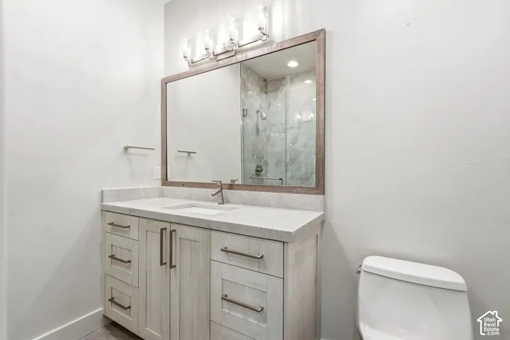 Vanity with integrated sink, light-toned countertop, wood-finish cabinetry, and a framed mirror