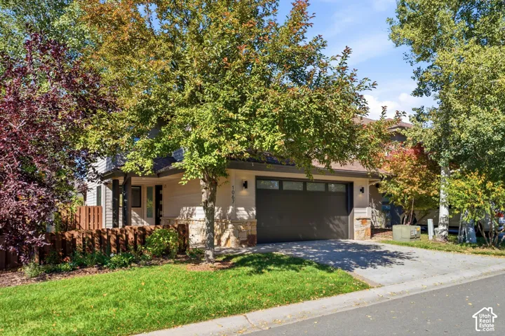 Attached garage with a dark finish door, stone accents on the facade, and a paved driveway