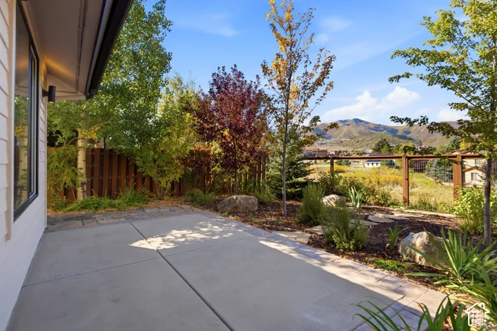 Concrete patio with a wood privacy fence, diverse landscaping, and mountain scenery