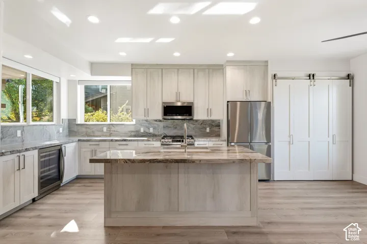 Kitchen with large center island, stainless steel appliances, recessed lighting, wood-finish flooring, and a barn door entry