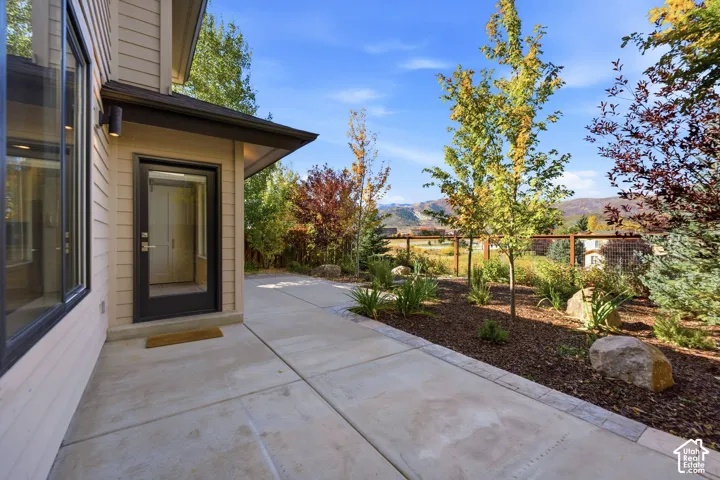 Concrete patio with a full-light entry door, a covered entry, and exterior wall sconces