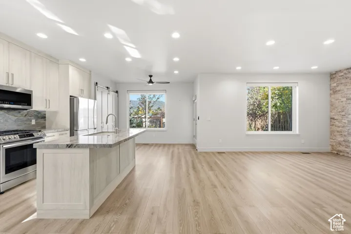 Kitchen with stainless steel appliances, a large island with an undermount sink, and light wood-finish cabinetry