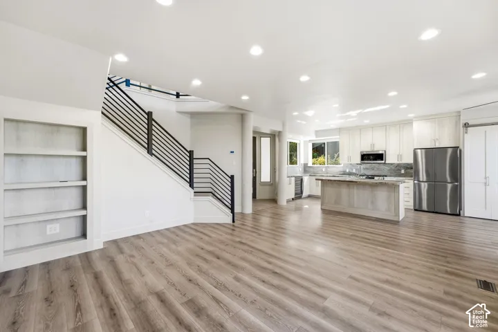 Spacious interior featuring wood-finish flooring, recessed lighting, and a modern kitchen with stainless steel appliances