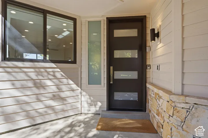 Contemporary entry door with frosted glass panels and a stainless steel pull handle, complemented by a stone veneer wall