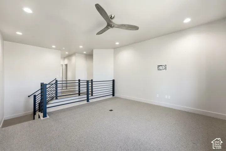 Recessed lighting, ceiling fan, carpeted flooring, and a contemporary metal railing system