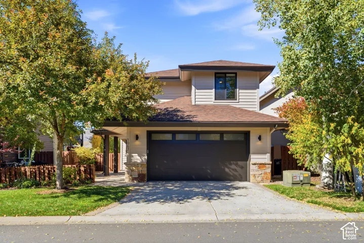 Contemporary exterior featuring horizontal siding, a dark garage door, and stone column accents