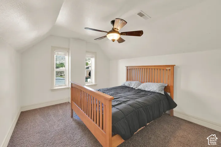 Sloped ceilings, two distinct windows, and a ceiling fan with integrated lighting