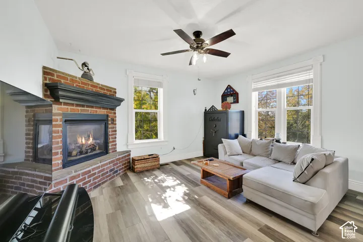 Brick-surround fireplace with a dark wood mantel, wood-finish flooring, and white window trim