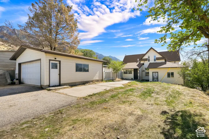 Two-story residence with a detached garage, gravel driveway, and prominent mountain backdrop
