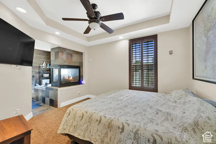 Tray ceiling with recessed lighting, ceiling fan, and brown plantation shutters