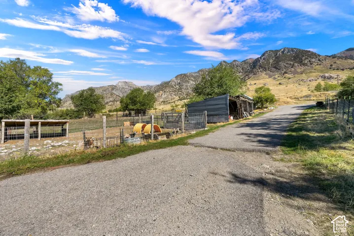 Gravel driveway with a fenced enclosure and mountain backdrop