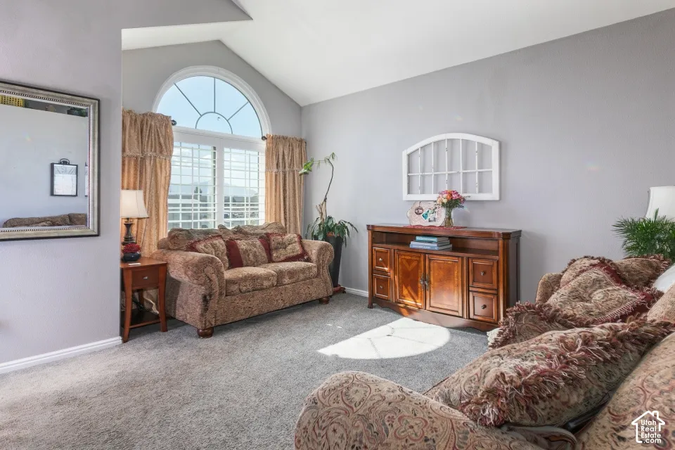 Vaulted ceiling, arched window, and carpeted flooring
