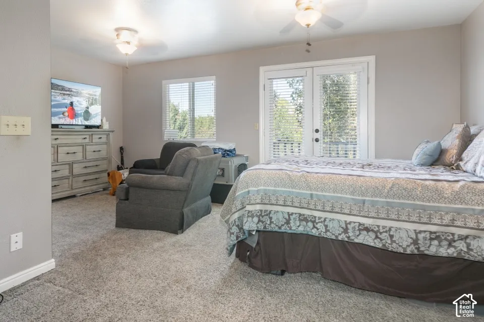 Carpeted room featuring a ceiling fan, window with blinds, and French doors