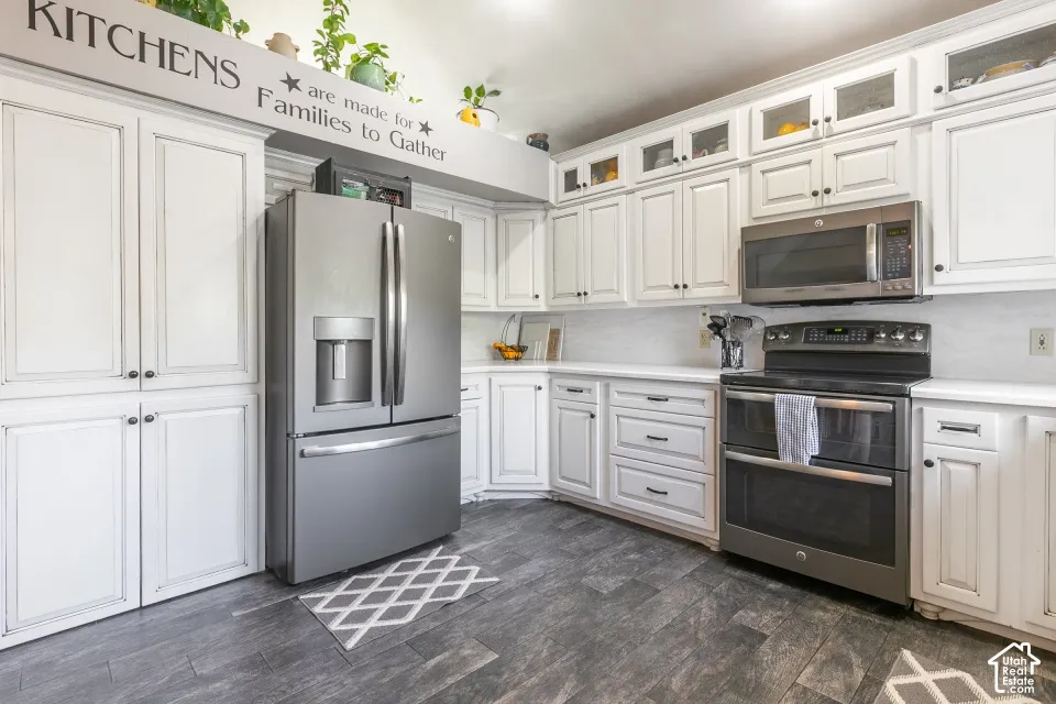 White cabinetry with black hardware, stainless steel appliances, and white countertops