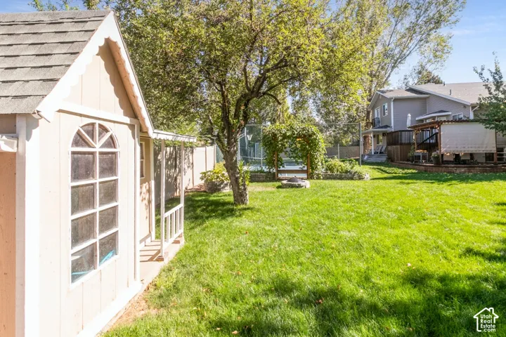 Expansive backyard featuring a manicured lawn, established trees, and a playhouse