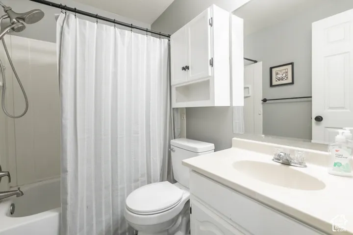 White vanity with integrated sink, chrome faucet, wall-mounted mirror, and overhead cabinetry