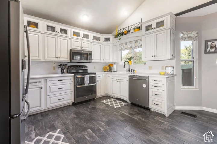 White cabinetry with dark hardware, stainless steel appliances, white countertops, white tile backsplash