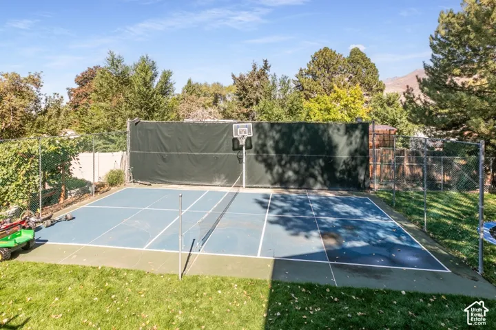Multi-sport court with a basketball hoop and net, surrounded by chain-link fencing