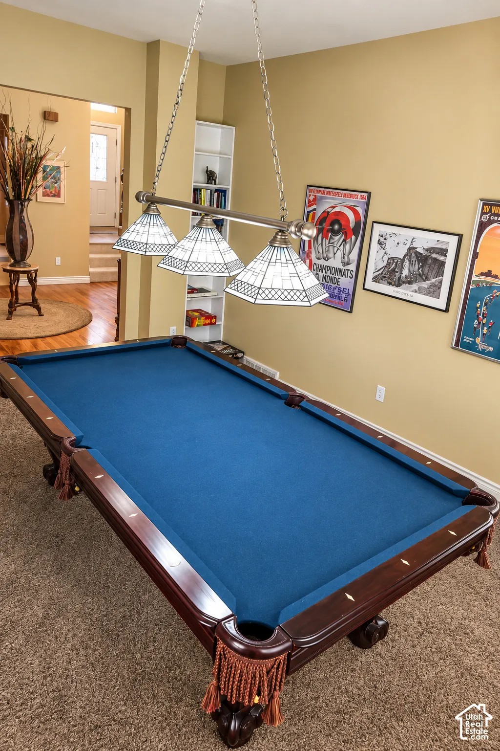 Carpeted recreation room featuring a built-in bookshelf and a multi-bulb hanging fixture with stained glass shades