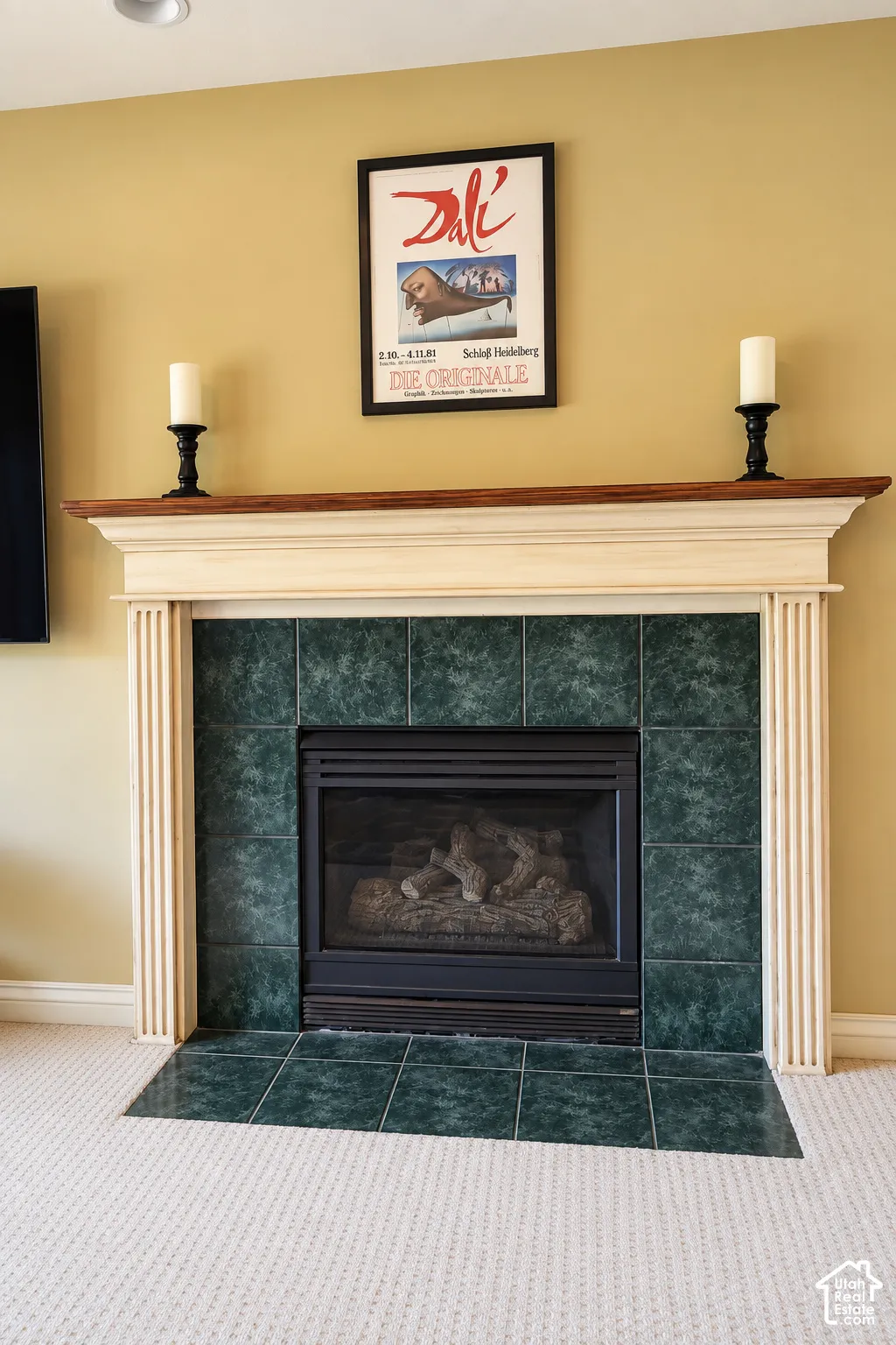 Fireplace featuring a decorative mantel, green tile surround, and an integrated firebox with log inserts