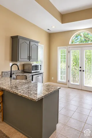 Kitchenette with a stone-finish countertop, stainless steel sink, and gray cabinetry