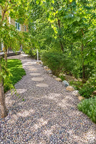 Charming gravel pathway lined with mature hedges and lush greenery, leading through the property grounds