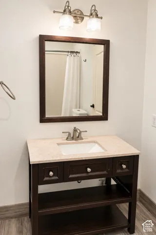 Elegant bathroom vanity featuring dark wood cabinetry with three drawers and open shelving, white marble-finish countertop with an undermount sink, and brushed nickel faucet