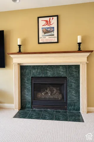 Fireplace featuring a decorative mantel, green tile surround, and an integrated firebox with log inserts